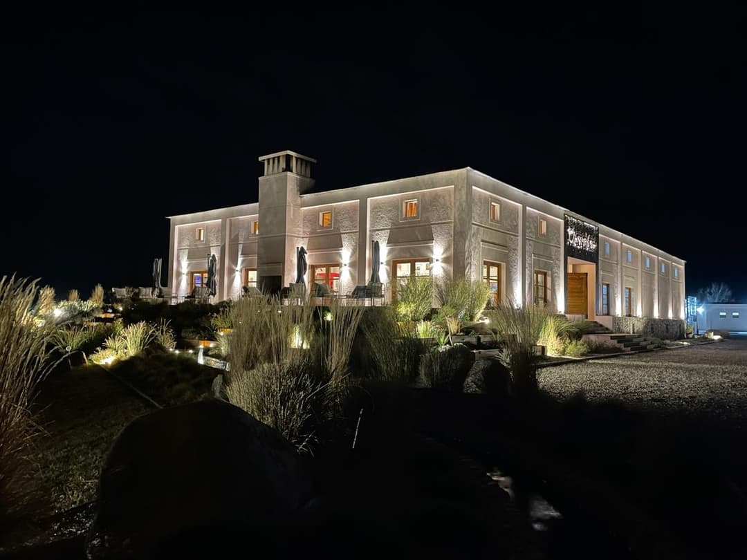 Bodega Claroscuro iluminada de noche, fachada cálida contra cielo oscuro